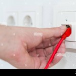 man-plugs-red-network-cable-in-wall-outlet-for-office-or-private-home-lan-ethernet-connection-with-power-outlets-flat-view-on-white-plaster-wall-backg-W16HC0